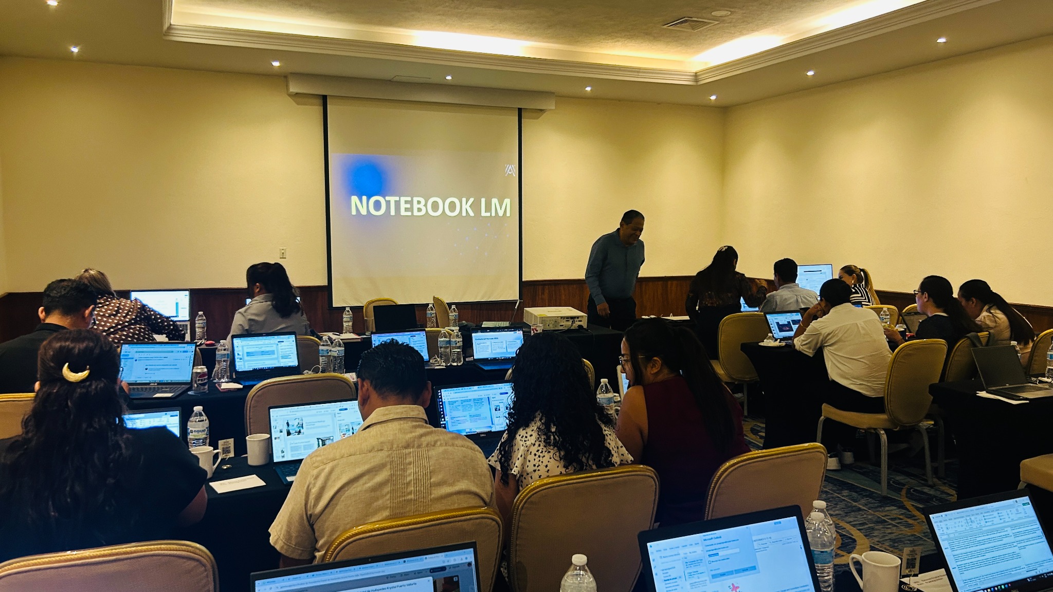 Equipo hotelero trabajando con computadoras durante un taller presencial de inteligencia artificial